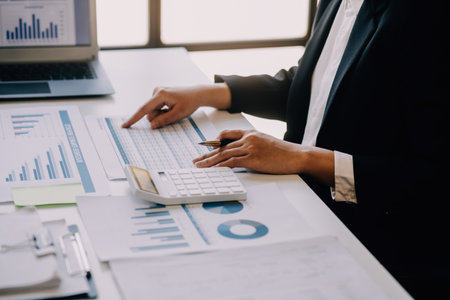 Woman accountant use calculator and computer with holding pen onの写真素材
