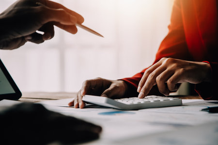 Financial analysts analyze business financial reports on a digital tablet planning investment project during a discussion at a meeting of corporate showing the results of their successful teamwork.の写真素材