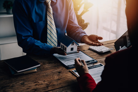 Real estate broker agent presenting and consult to customer to decision making sign insurance form agreement, buy and sell home model, concerning mortgage loan offer for and house insuranceの写真素材