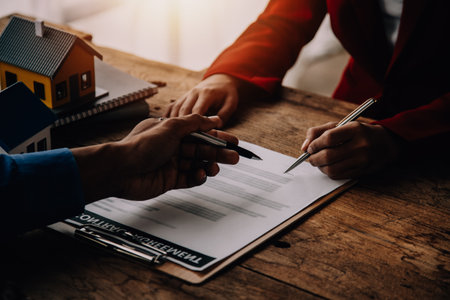 Real estate broker agent presenting and consult to customer to decision making sign insurance form agreement, buy and sell home model, concerning mortgage loan offer for and house insuranceの写真素材