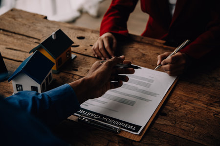 Real estate broker agent presenting and consult to customer to decision making sign insurance form agreement, buy and sell home model, concerning mortgage loan offer for and house insuranceの写真素材