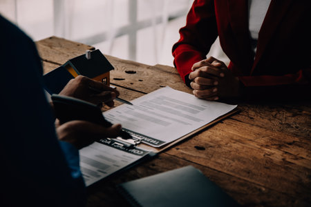 Real estate broker agent presenting and consult to customer to decision making sign insurance form agreement, buy and sell home model, concerning mortgage loan offer for and house insuranceの写真素材