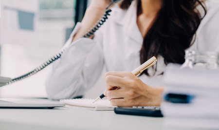 Asian Business woman using calculator and laptop for doing math finance on an office desk, tax, report, accounting, statistics, and analytical research conceptの写真素材