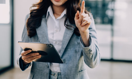 Asian Business woman using calculator and laptop for doing math finance on an office desk, tax, report, accounting, statistics, and analytical research conceptの写真素材