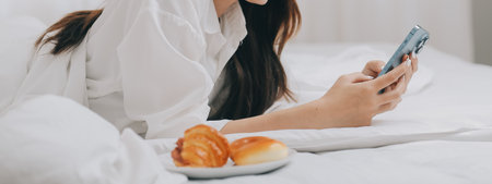 Happy freelance asian woman work on tablet on the hotel bed on travel trip.の写真素材
