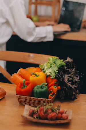 Portrait of pretty freelancer female working typing on laptop computer sitting at table smiling looking to screen in kitchen. Attractive redhead young woman remote working on laptop from home office.の写真素材