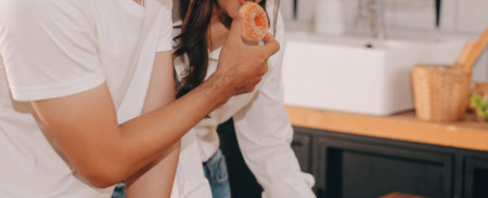Handsome man sitting near his wife at kitchen. Family couple see social media, surf the web while sitting at kitchen table with generic laptop. Couple working with laptop at homeの写真素材