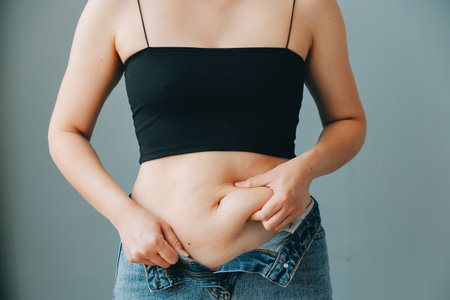 fat woman, fat belly, chubby, obese woman hand holding excessive belly fat with measure tape, woman diet lifestyle conceptの写真素材