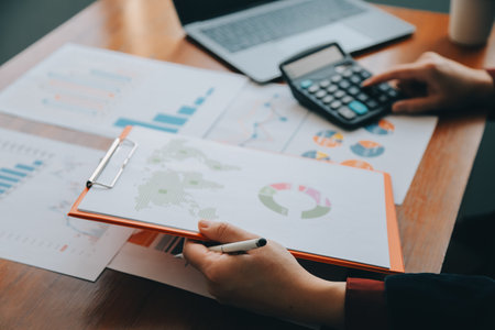 Group of confident business people point to graphs and charts to analyze market data, balance sheet, account, net profit to plan new sales strategies to increase production capacity.の写真素材