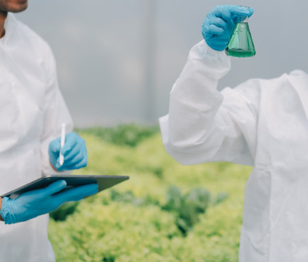 Man and woman use a test tube and a pipette while working in a greenhouse.の写真素材