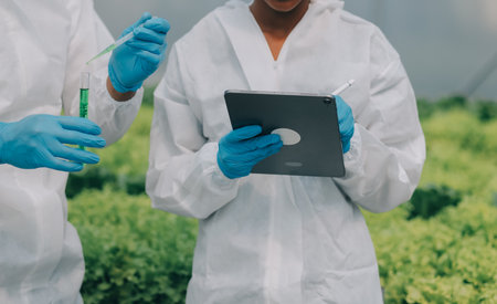Man and woman use a test tube and a pipette while working in a greenhouse.の写真素材