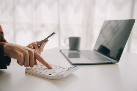 Close up Business woman using calculator and laptop for do math finance on wooden desk, tax, accounting, statistics and analytical research conceptの写真素材