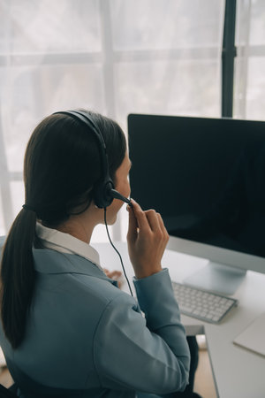 Beautiful female call center operator working on computer in officeの写真素材