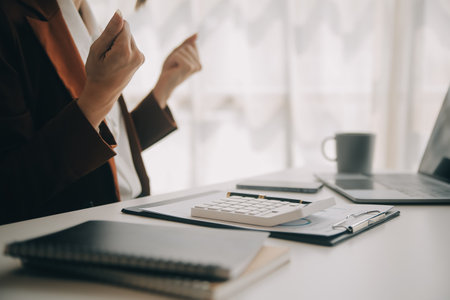 Close up Business woman using calculator and laptop for do math finance on wooden desk, tax, accounting, statistics and analytical research conceptの写真素材