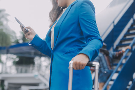 Young asian woman in international airport, using mobile smartphone and checking flight at the flight information boardの写真素材
