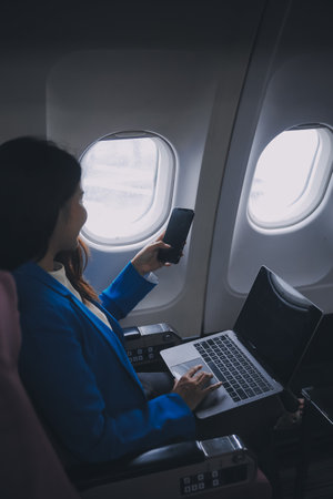 Using mobile and laptop, Thoughtful asian people female person onboard, airplane window, perfectly capture the anticipation and excitement of holiday travel. chinese, japanese people.の写真素材