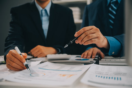 Financial analysts analyze business financial reports on a digital tablet planning investment project during a discussion at a meeting of corporate showing the results of their successful teamwork.の写真素材