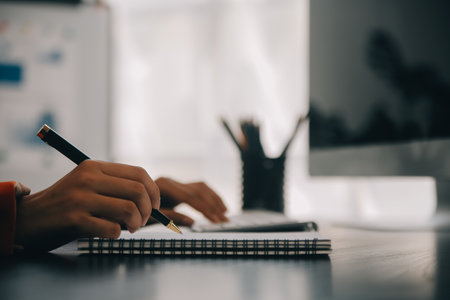 Asian Business woman using calculator and laptop for doing math finance on an office desk, tax, report, accounting, statistics, and analytical research conceptの写真素材