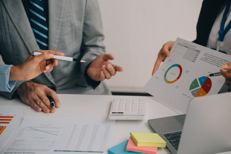 Financial analysts analyze business financial reports on a digital tablet planning investment project during a discussion at a meeting of corporate showing the results of their successful teamwork.の写真素材