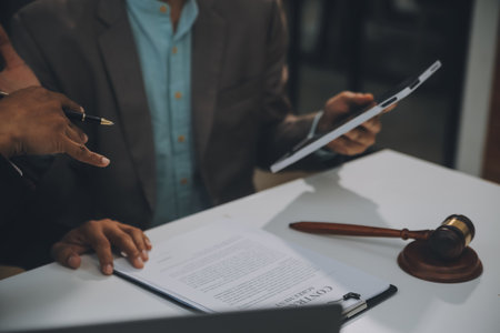 Business and lawyers discussing contract papers with brass scale on desk in office. Law, legal services, advice, justice and law concept picture with film grain effectの写真素材