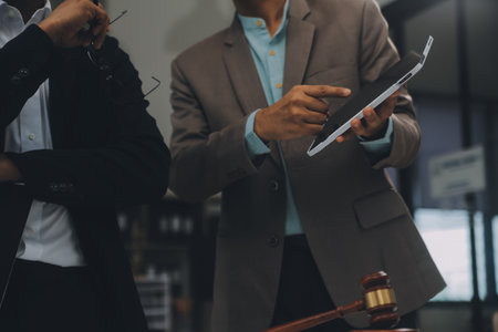Business and lawyers discussing contract papers with brass scale on desk in office. Law, legal services, advice, justice and law concept picture with film grain effectの写真素材