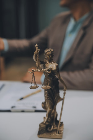 Business and lawyers discussing contract papers with brass scale on desk in office. Law, legal services, advice, justice and law concept picture with film grain effectの写真素材