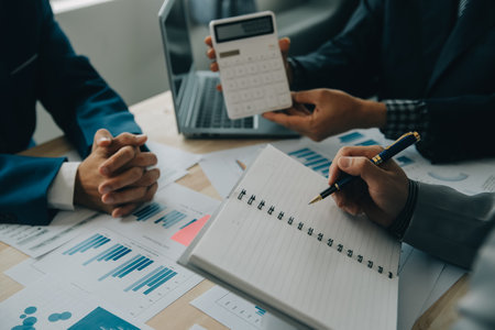 Financial analysts analyze business financial reports on a digital tablet planning investment project during a discussion at a meeting of corporate showing the results of their successful teamwork.の写真素材
