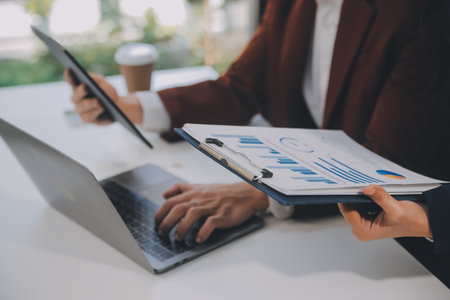 Financial analysts analyze business financial reports on a digital tablet planning investment project during a discussion at a meeting of corporate showing the results of their successful teamwork.の写真素材