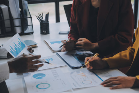 Financial analysts analyze business financial reports on a digital tablet planning investment project during a discussion at a meeting of corporate showing the results of their successful teamwork.の写真素材