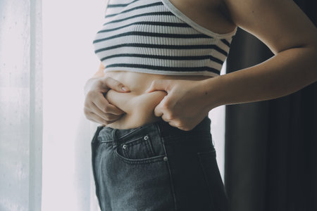 Women body fat belly. Obese woman hand holding excessive belly fat. diet lifestyle concept to reduce belly and shape up healthy stomach muscle.の写真素材