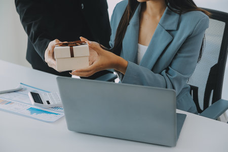 Young businessman giving his colleague present in office. Young man surprise beautiful businesswoman in office.の写真素材