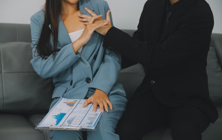 Sexsual harassment in workplace. Unhappy female employee looking at hand of boss touch at her shoulder and feeling disgusted.の写真素材