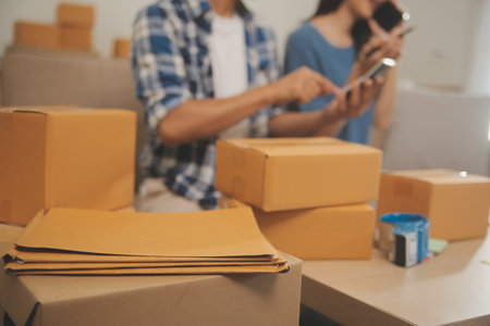 Two Asian blogger showing clothes in front of the camera to recording vlog video live streaming at her shop. Online Shopping Cart notion. on sofa at homeの写真素材