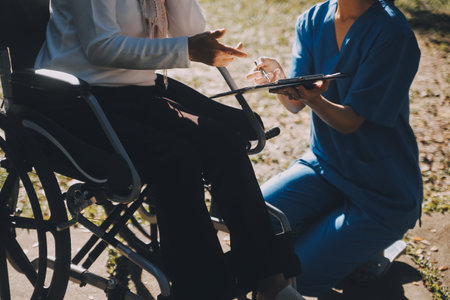Nursing staff talking to an elderly person sitting in a wheelchair.の写真素材