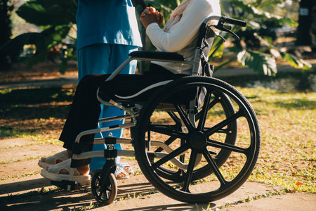 Nursing staff talking to an elderly person sitting in a wheelchair.の写真素材