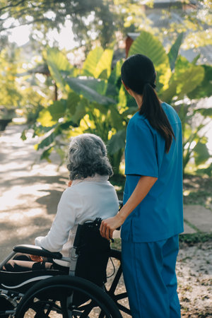 A nurse take care a senior male on wheelchair in his garden at homeの写真素材