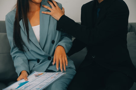 Sexsual harassment in workplace. Unhappy female employee looking at hand of boss touch at her shoulder and feeling disgusted.の写真素材