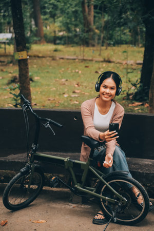 Happy young Asian woman while riding a bicycle in a city park. She smiled using the bicycle of transportation. Environmentally friendly concept.の写真素材