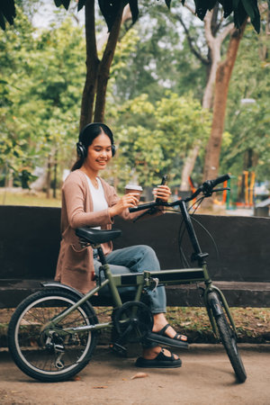 Happy young Asian woman while riding a bicycle in a city park. She smiled using the bicycle of...