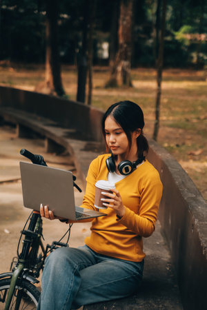 Happy young Asian woman while riding a bicycle in a city park. She smiled using the bicycle of transportation. Environmentally friendly concept.の写真素材
