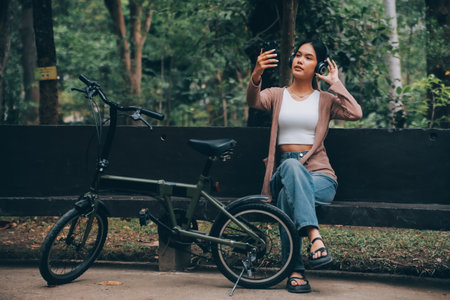 Happy young Asian woman while riding a bicycle in a city park. She smiled using the bicycle of transportation. Environmentally friendly concept.の写真素材