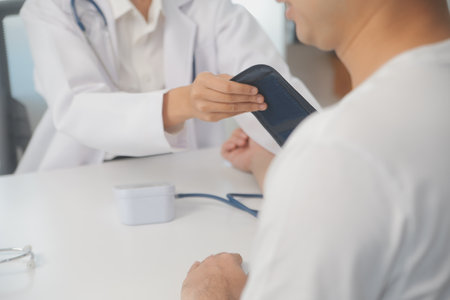 Male doctor uses a blood pressure monitor to check the body pressure and pulse of the patients who come to the hospital for check-ups, Medical treatment and health care concept.の写真素材