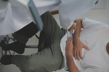 Man suffering with severe stomach pain sitting at home. Hand of mature guy holding abdomen suffering from ache, diarrhea or indigestive problem. Caucasian guy pressing on belly on painful sensationの写真素材