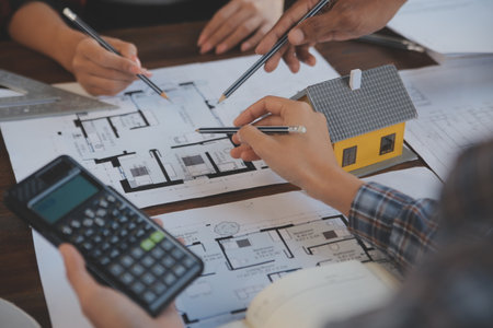 A team of construction engineers talks to managers and construction workers at the construction...