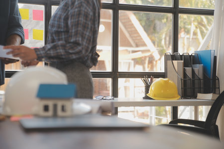 A team of construction engineers talks to managers and construction workers at the construction site. Quality inspection, work plan, home and industrial building design projectの写真素材