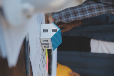 A team of construction engineers talks to managers and construction workers at the construction site. Quality inspection, work plan, home and industrial building design projectの写真素材