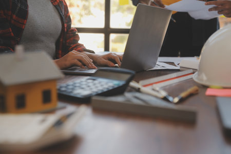A team of construction engineers talks to managers and construction workers at the construction site. Quality inspection, work plan, home and industrial building design projectの写真素材