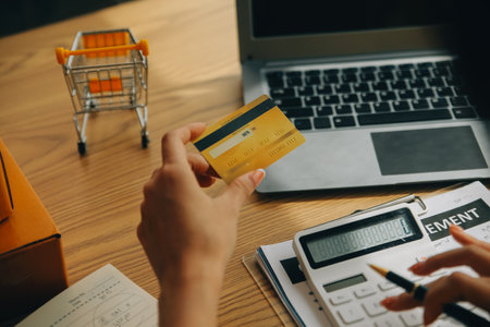 Young woman holding a smartphone, tablet showing payment success and credit card with yellow parcel...