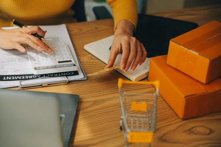 Young woman holding a smartphone, tablet showing payment success and credit card with yellow parcel...