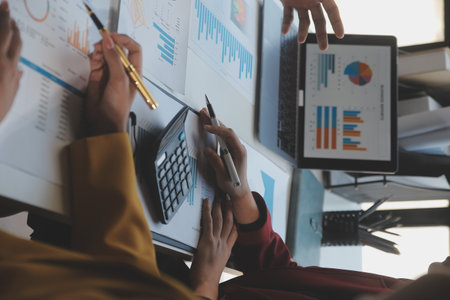 Financial analysts analyze business financial reports on a digital tablet planning investment project during a discussion at a meeting of corporate showing the results of their successful teamwork.の写真素材
